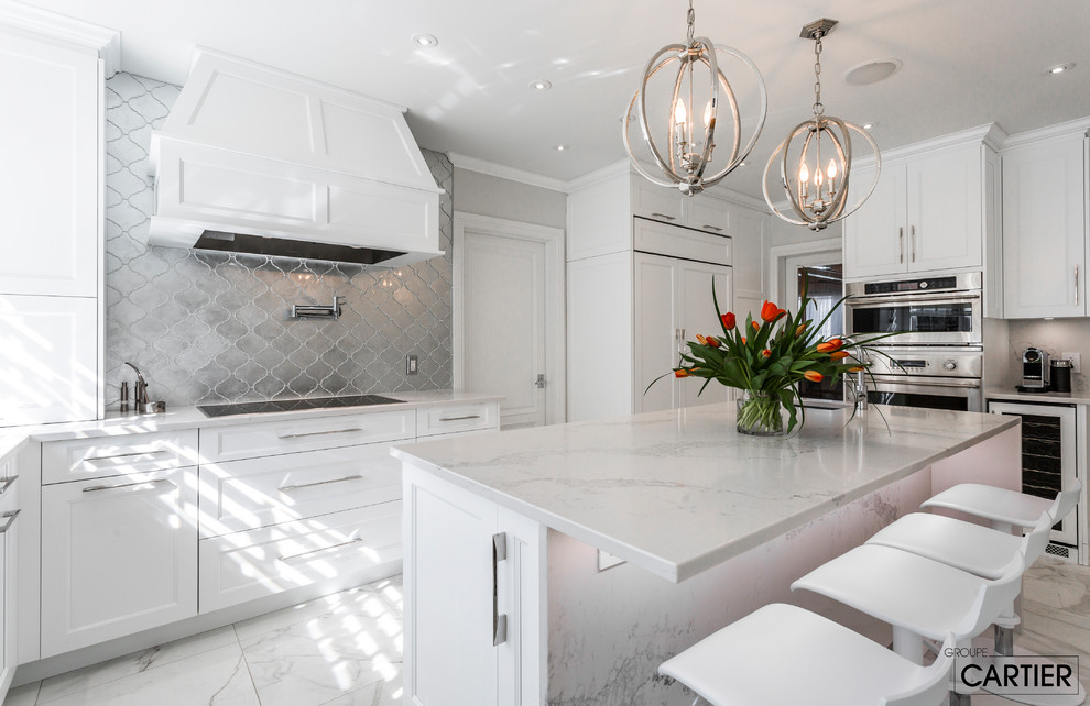 Photo of an expansive transitional l-shaped eat-in kitchen in Montreal with an undermount sink, shaker cabinets, white cabinets, quartzite benchtops, grey splashback, glass tile splashback, panelled appliances, marble floors and with island.