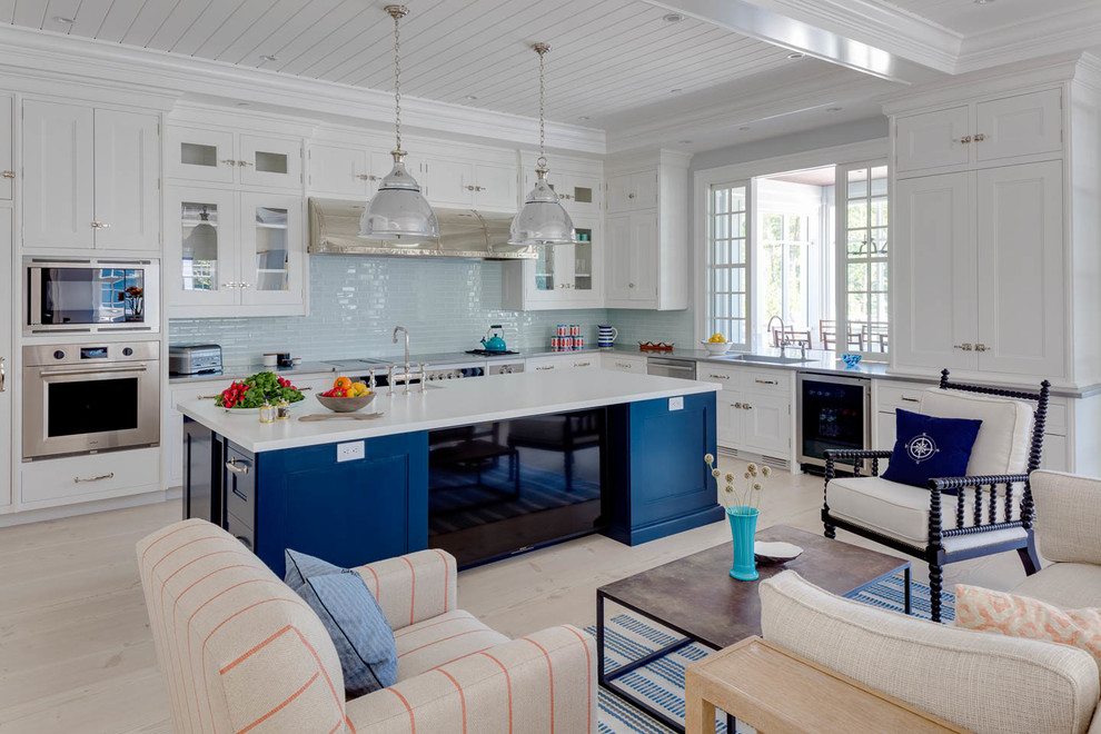 Beach style l-shaped kitchen in Boston with recessed-panel cabinets, white cabinets, blue splashback, light hardwood floors, with island, beige floor and white benchtop.