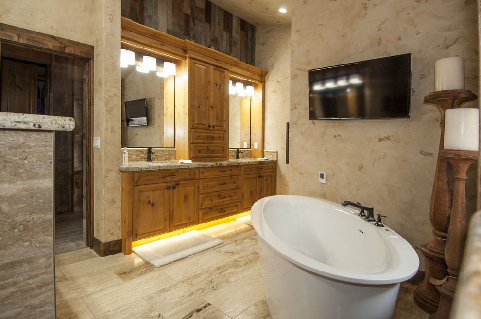Example of a mid-sized transitional stone tile freestanding bathtub design with an undermount sink, raised-panel cabinets, medium tone wood cabinets, granite countertops and a two-piece toilet
