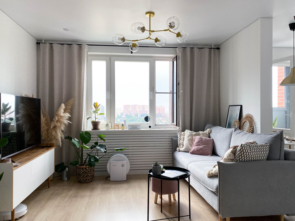 Imagen de salón blanco y madera escandinavo de tamaño medio con paredes blancas, suelo laminado y televisor independiente