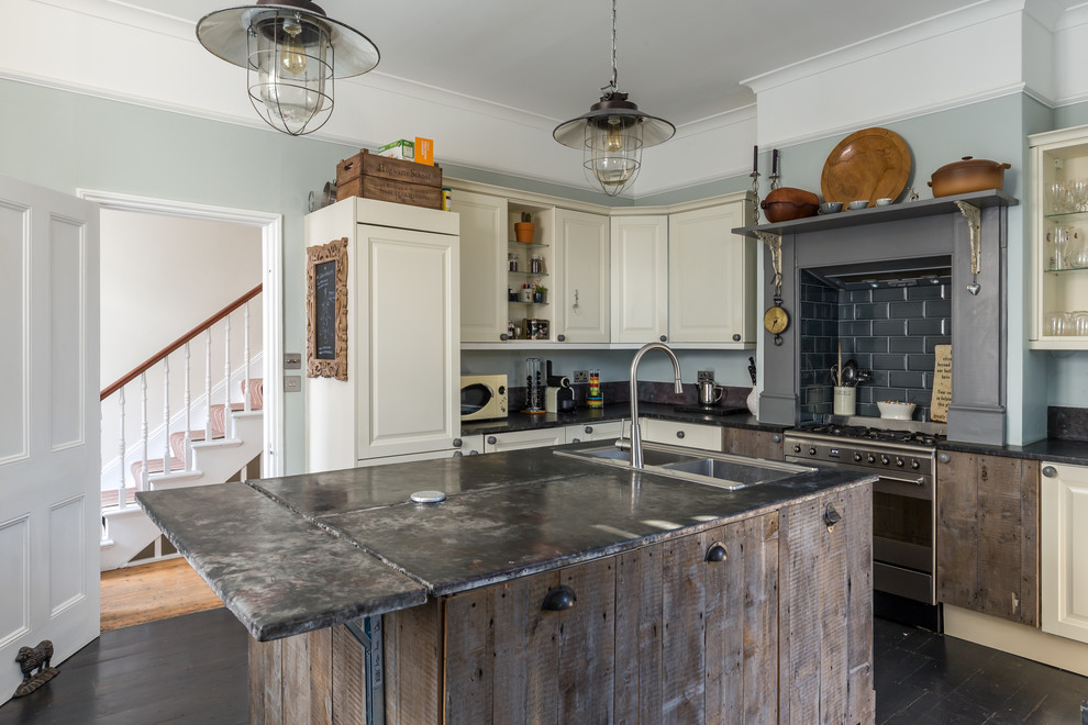 Mid-sized industrial l-shaped kitchen in Sussex with a double-bowl sink, raised-panel cabinets, white cabinets, black splashback, subway tile splashback, stainless steel appliances, with island, black floor, black benchtop and dark hardwood floors.