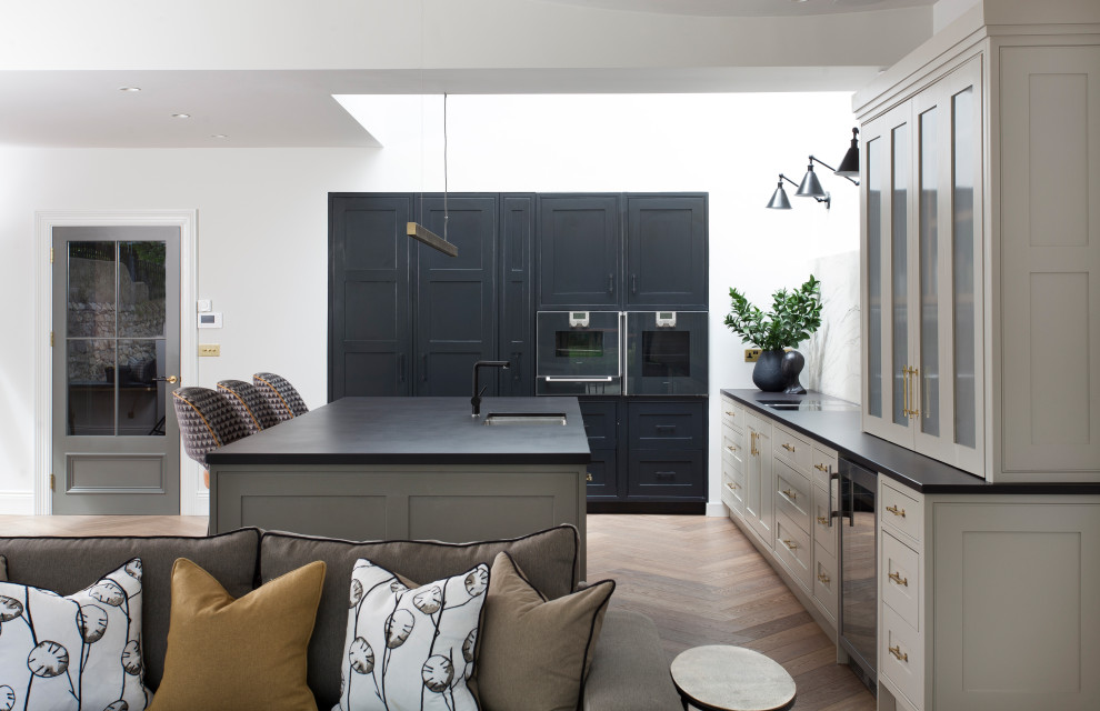 Inspiration för ett 60 tals svart svart kök med öppen planlösning, med en enkel diskho, svarta skåp, bänkskiva i kvarts, grönt stänkskydd, stänkskydd i marmor, en köksö och brunt golv