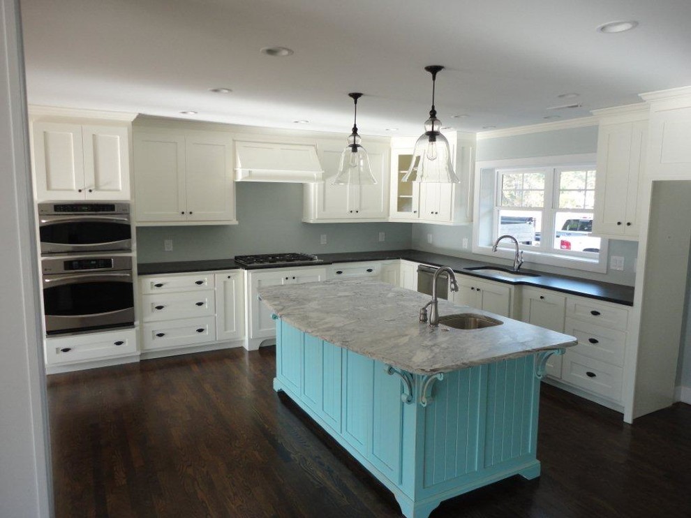 This is an example of a large beach style l-shaped separate kitchen in Other with an undermount sink, shaker cabinets, white cabinets, stainless steel appliances, dark hardwood floors, with island and brown floor.