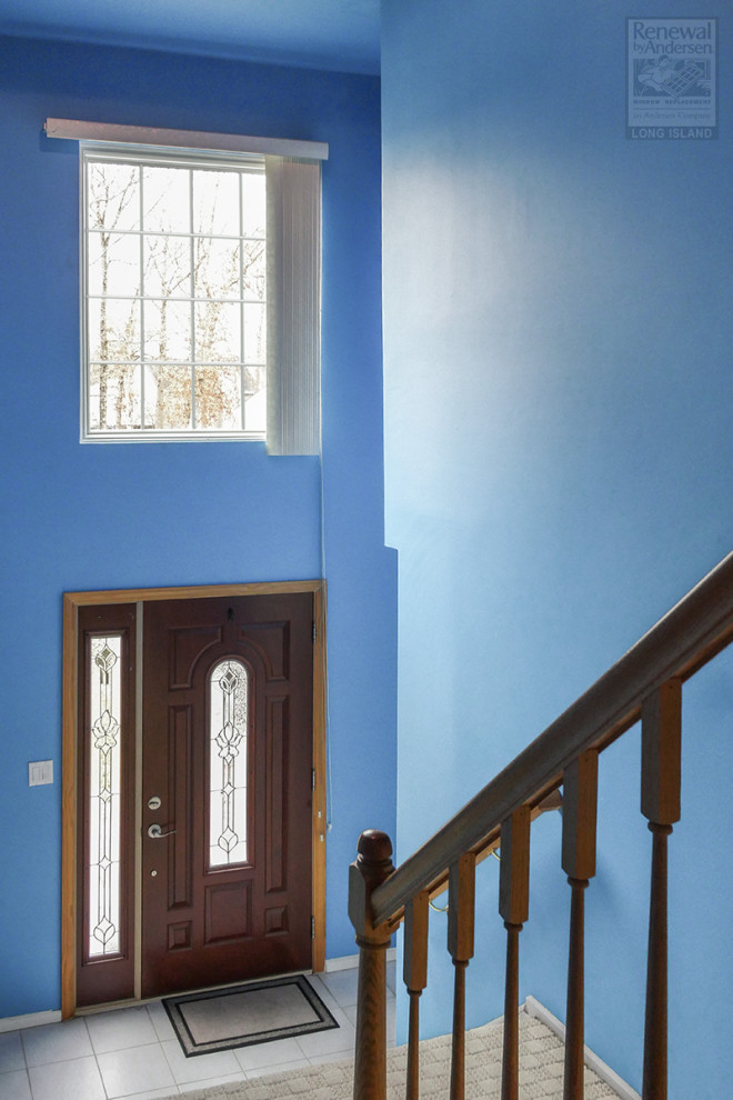This is an example of a medium sized front door in New York with blue walls, ceramic flooring, a single front door, a dark wood front door, grey floors and a vaulted ceiling.
