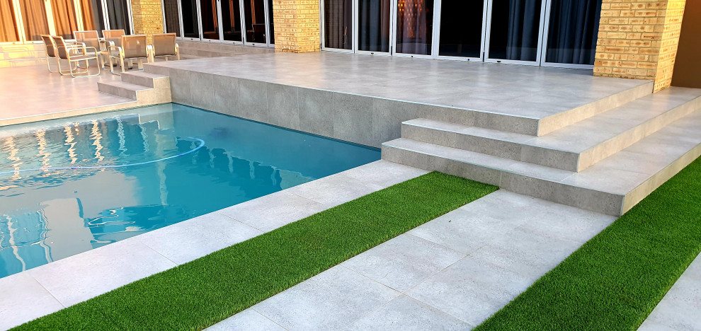 Idee per una grande piscina minimalista rettangolare dietro casa con paesaggistica bordo piscina e piastrelle