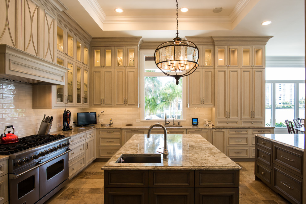 Large transitional u-shaped travertine floor and beige floor kitchen photo with an undermount sink, raised-panel cabinets, brown cabinets, quartzite countertops, white backsplash, subway tile backsplash, paneled appliances and two islands