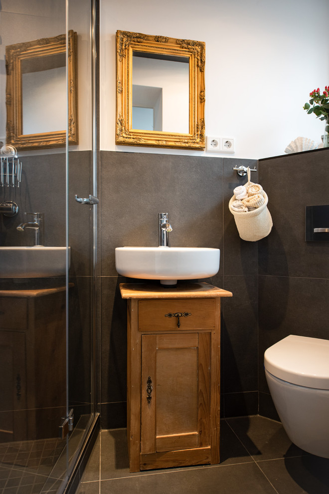 Inspiration för moderna badrum, med skåp i ljust trä, en kantlös dusch, en vägghängd toalettstol, grå kakel, keramikplattor, vita väggar, kalkstensgolv, ett väggmonterat handfat, grått golv och dusch med gångjärnsdörr