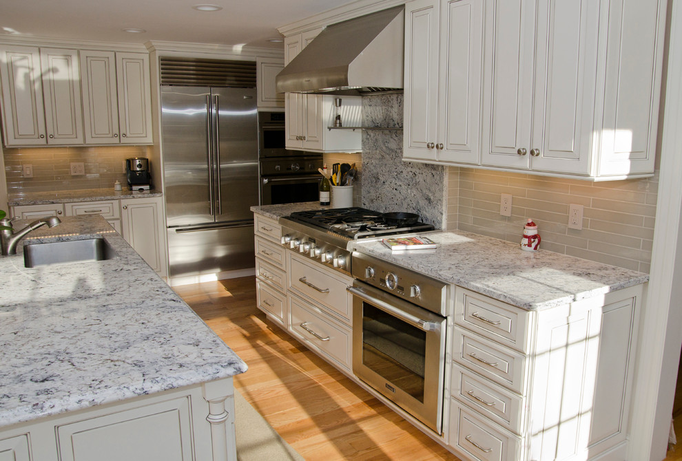 Traditional kitchen in Boston with recessed-panel cabinets, white cabinets, laminate benchtops, black splashback, ceramic splashback and white appliances.
