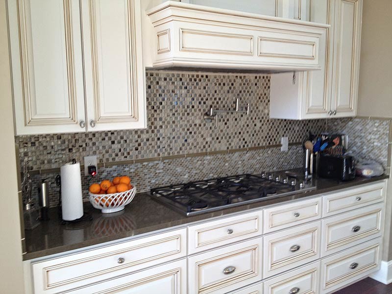 Example of a transitional medium tone wood floor kitchen design in Austin with white cabinets, gray backsplash, black appliances and an island