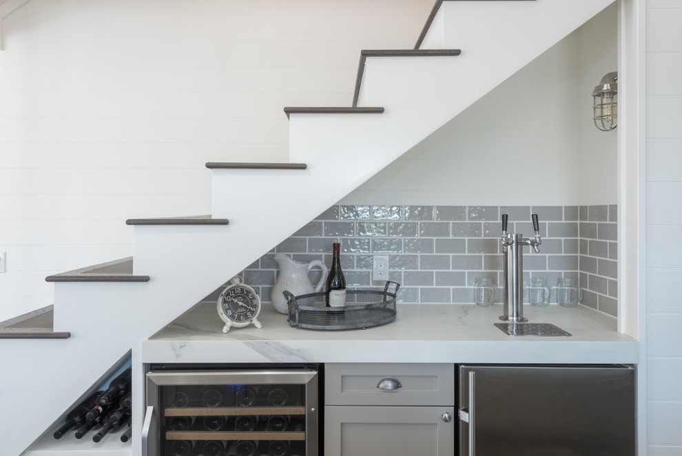 This is an example of a large transitional home bar in San Francisco with flat-panel cabinets, white cabinets, tile benchtops, grey splashback, ceramic splashback and medium hardwood floors.