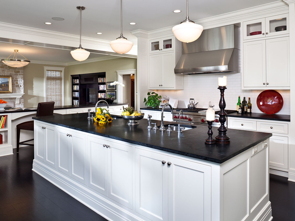 This is an example of a large traditional l-shaped separate kitchen in Minneapolis with an undermount sink, shaker cabinets, white cabinets, soapstone benchtops, white splashback, subway tile splashback, stainless steel appliances, dark hardwood floors, with island, black floor and black benchtop.