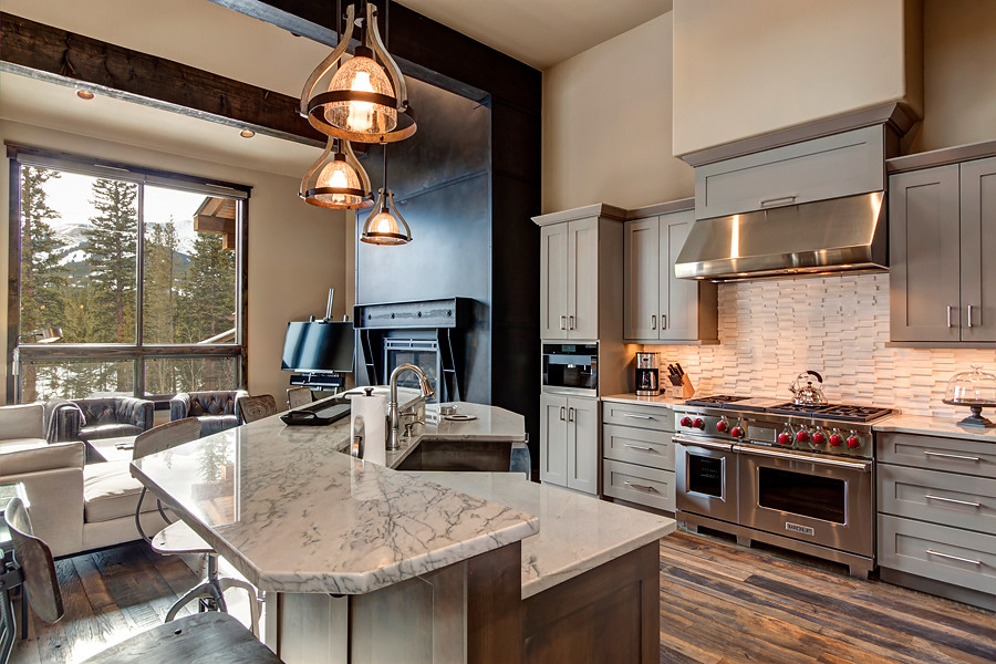 U-shaped medium tone wood floor eat-in kitchen photo in Denver with a farmhouse sink, recessed-panel cabinets, gray cabinets, marble countertops, white backsplash, ceramic backsplash, stainless steel appliances and an island