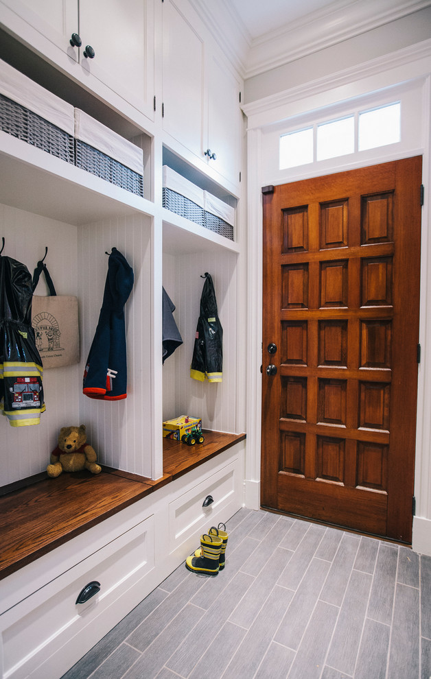 This is an example of a traditional mudroom in Chicago with white walls, ceramic floors and a single front door.