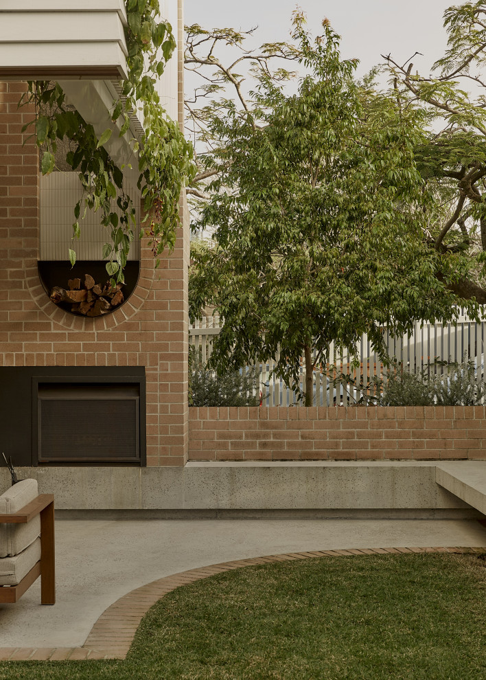 Foto di un patio o portico contemporaneo dietro casa con un caminetto e lastre di cemento