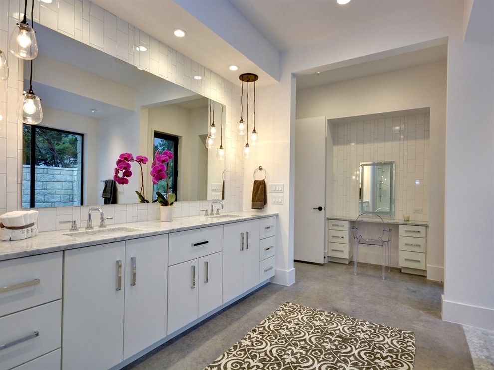 Design ideas for a large contemporary master bathroom in Austin with flat-panel cabinets, white cabinets, a freestanding tub, an alcove shower, white tile, ceramic tile, white walls, concrete floors and an undermount sink.