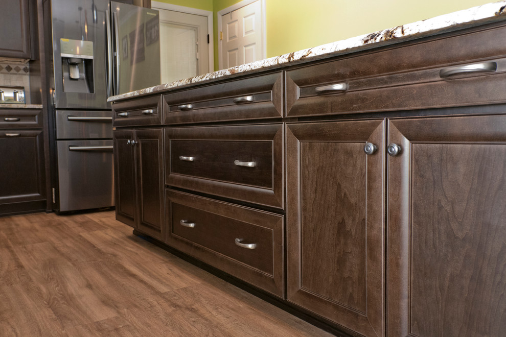 Inspiration for a large transitional l-shaped eat-in kitchen in Baltimore with an undermount sink, recessed-panel cabinets, dark wood cabinets, granite benchtops, beige splashback, mosaic tile splashback, stainless steel appliances, vinyl floors, with island and brown floor.