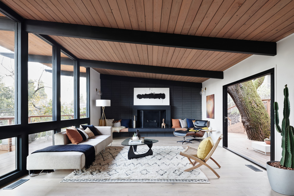 This is an example of a midcentury open concept living room in San Francisco with white walls, a standard fireplace, grey floor, exposed beam, vaulted and wood.