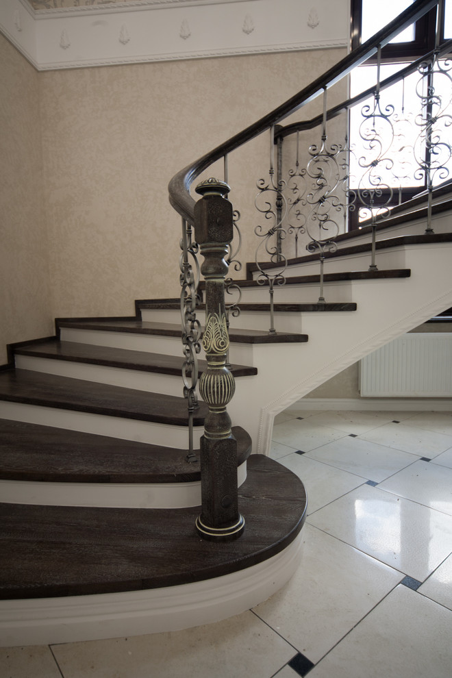 Бетонная лестница со ступенями из дуба и кованными балясинаями