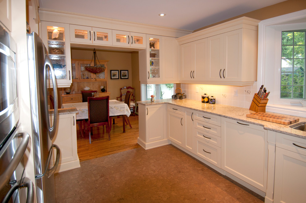 This is an example of a mid-sized traditional u-shaped eat-in kitchen in Ottawa with an undermount sink, beige cabinets, quartz benchtops, white splashback, ceramic splashback, stainless steel appliances, cork floors, shaker cabinets and no island.