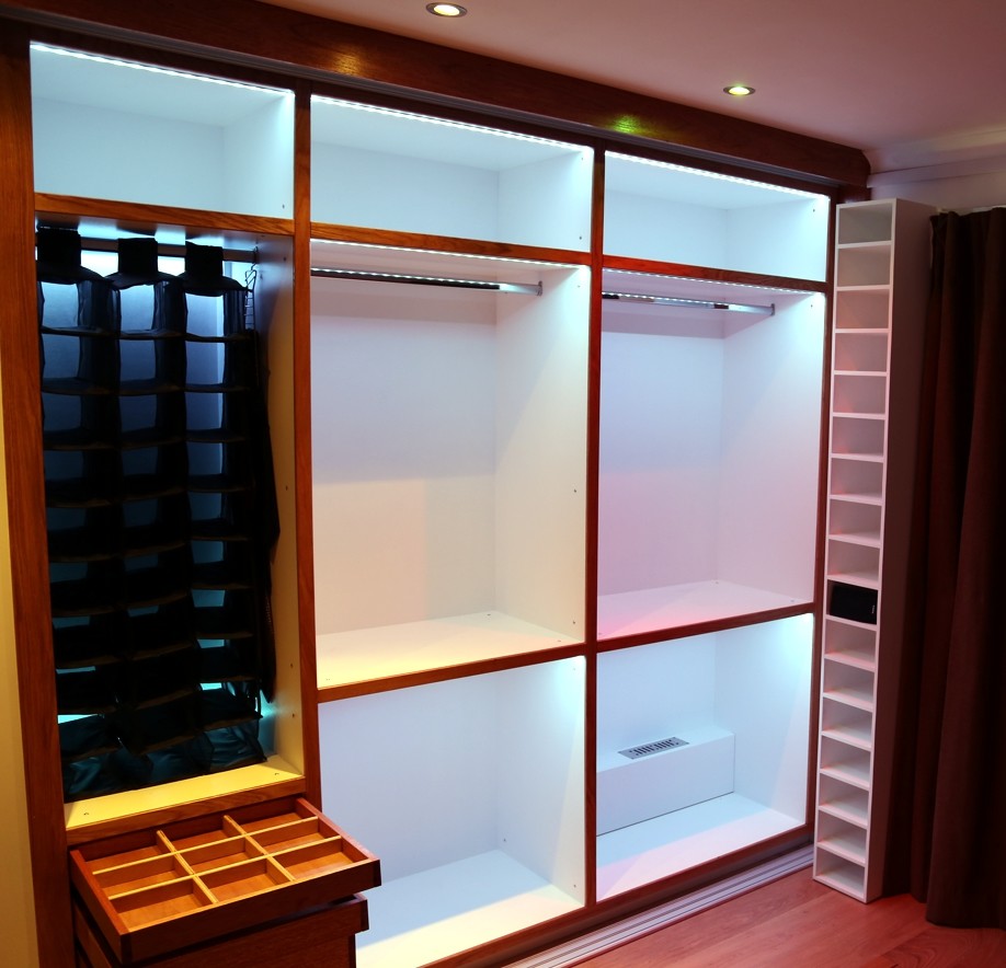 This is an example of a small contemporary built-in wardrobe in Buckinghamshire with medium hardwood floors.