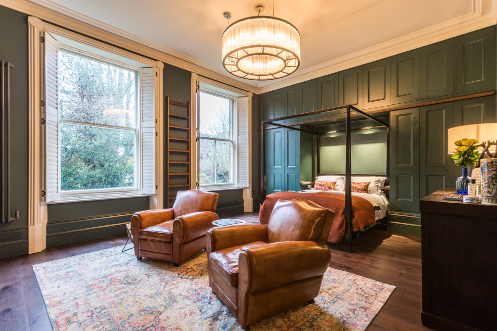 This is an example of a large traditional master bedroom in London with green walls, dark hardwood floors and brown floor.