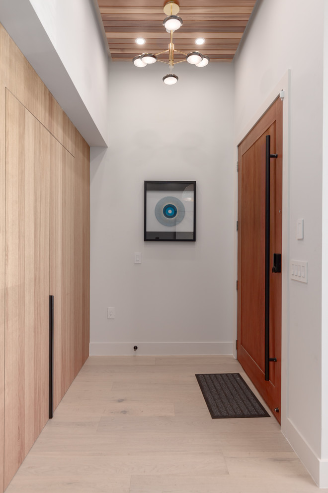Inspiration for a small contemporary front door in Vancouver with white walls, light hardwood floors, a single front door, a medium wood front door and yellow floor.