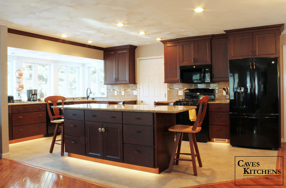 Eat-in kitchen - mid-sized transitional l-shaped vinyl floor eat-in kitchen idea with an undermount sink, flat-panel cabinets, dark wood cabinets, quartz countertops, beige backsplash, ceramic backsplash, black appliances and an island
