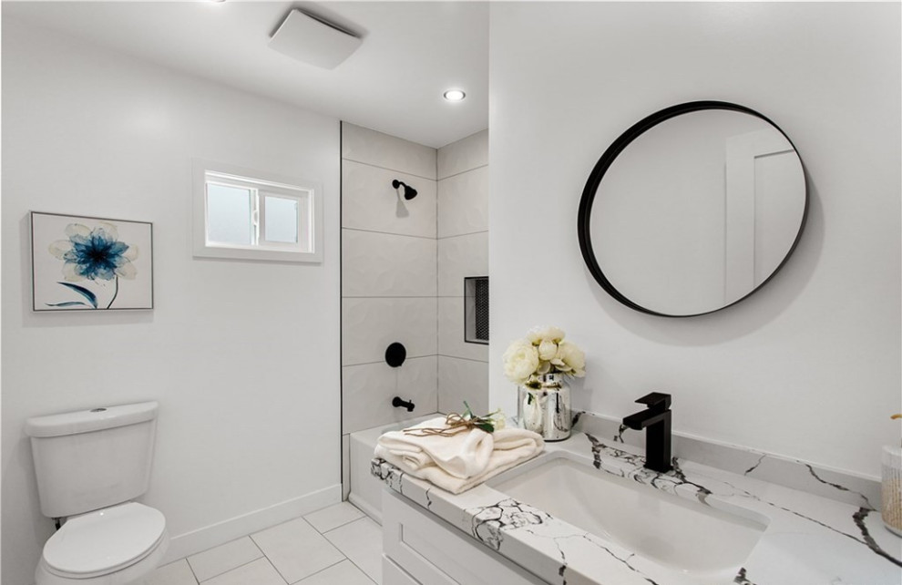 Design ideas for a classic bathroom in Los Angeles with shaker cabinets, white cabinets, an alcove bath, a shower/bath combination, a one-piece toilet, white walls, ceramic flooring, a submerged sink, marble worktops, white floors, a shower curtain, white worktops, a wall niche, a single sink and a built in vanity unit.