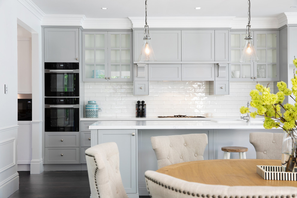 This is an example of a large beach style galley eat-in kitchen in Sydney with a farmhouse sink, shaker cabinets, grey cabinets, marble benchtops, white splashback, subway tile splashback, dark hardwood floors, with island and white benchtop.