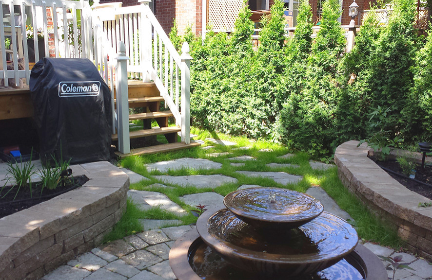 Geometrischer, Kleiner, Halbschattiger Klassischer Garten im Sommer, hinter dem Haus mit Hochbeet, Pflastersteinen und Holzzaun in Montreal