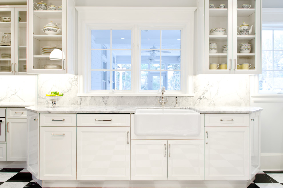 Mid-sized transitional eat-in kitchen in New York with a farmhouse sink, glass-front cabinets, white cabinets, quartzite benchtops, white splashback, stone slab splashback, panelled appliances and marble floors.