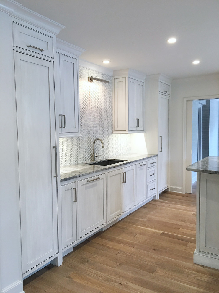 Inspiration for a large transitional l-shaped medium tone wood floor and brown floor eat-in kitchen remodel with an undermount sink, flat-panel cabinets, gray cabinets, marble countertops, gray backsplash, marble backsplash, paneled appliances and an island