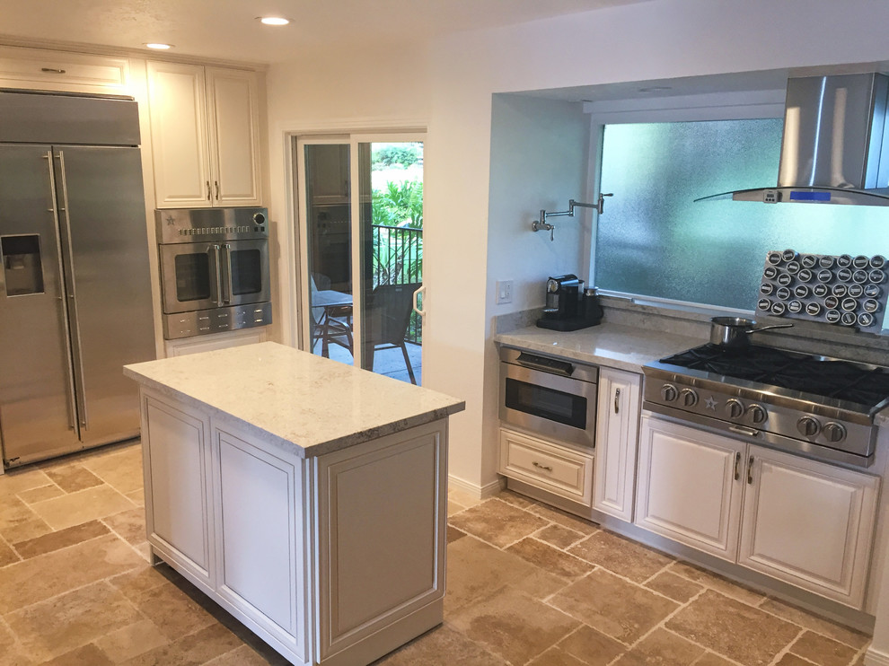 This is an example of a mid-sized traditional u-shaped eat-in kitchen in San Diego with an undermount sink, raised-panel cabinets, distressed cabinets, quartz benchtops, multi-coloured splashback, stone slab splashback, stainless steel appliances, travertine floors, with island and beige floor.
