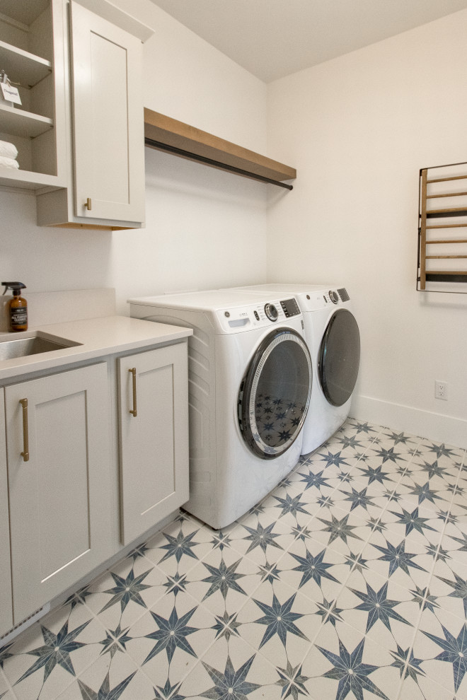 This is an example of a classic l-shaped separated utility room in Other with a submerged sink, recessed-panel cabinets, engineered stone countertops, white walls, porcelain flooring, a side by side washer and dryer and white worktops.
