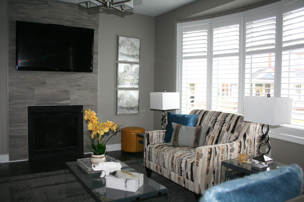 Photo of a mid-sized contemporary open concept family room in Ottawa with grey walls, dark hardwood floors, a standard fireplace, a tile fireplace surround, a wall-mounted tv and grey floor.