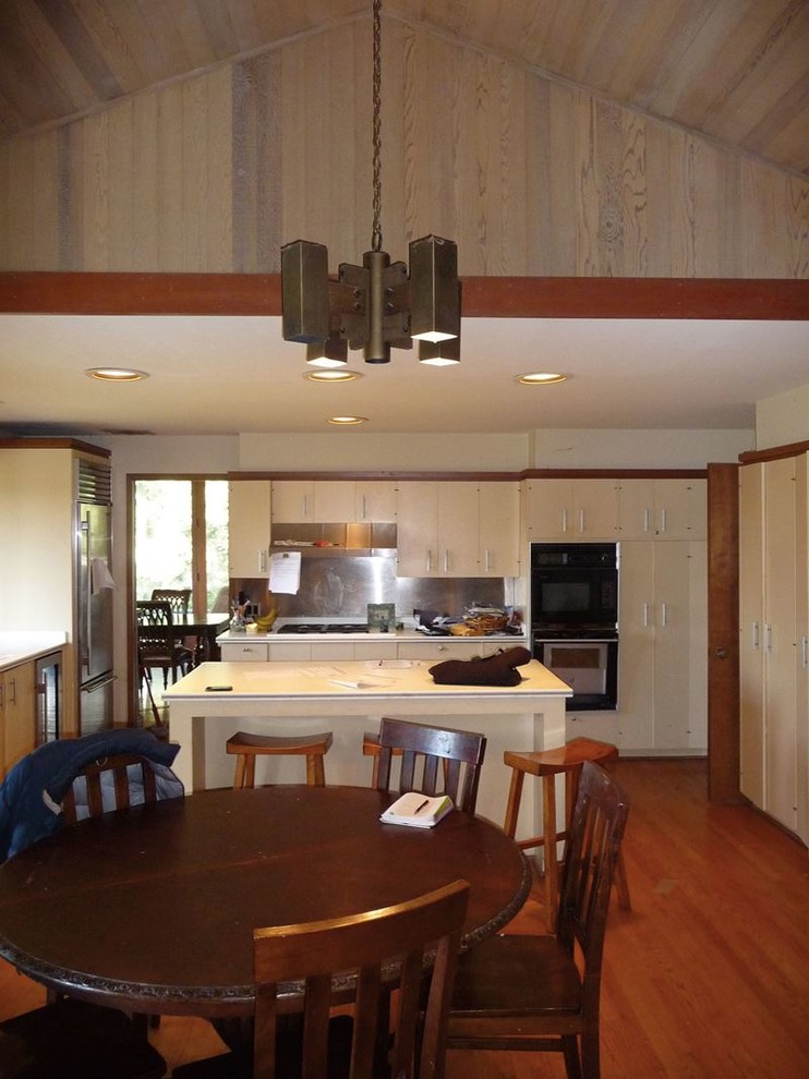 Inspiration for a large transitional u-shaped medium tone wood floor and brown floor open concept kitchen remodel in Austin with flat-panel cabinets, white cabinets, stainless steel appliances and an island