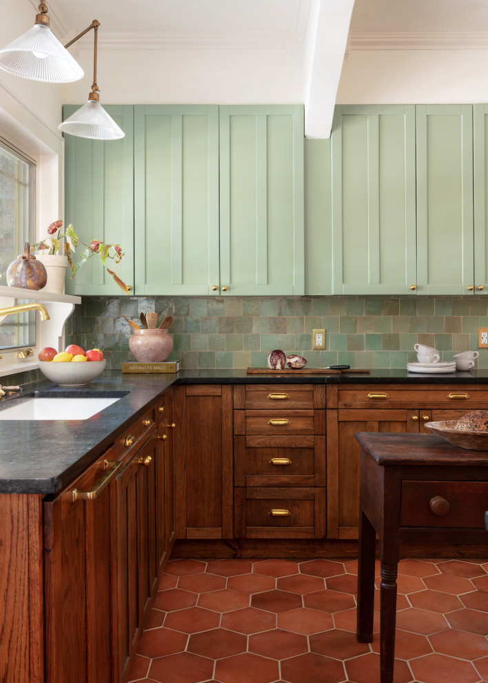 Mid-sized transitional u-shaped separate kitchen in Other with an undermount sink, shaker cabinets, medium wood cabinets, soapstone benchtops, green splashback, ceramic splashback, panelled appliances, terra-cotta floors, with island, black benchtop and exposed beam.