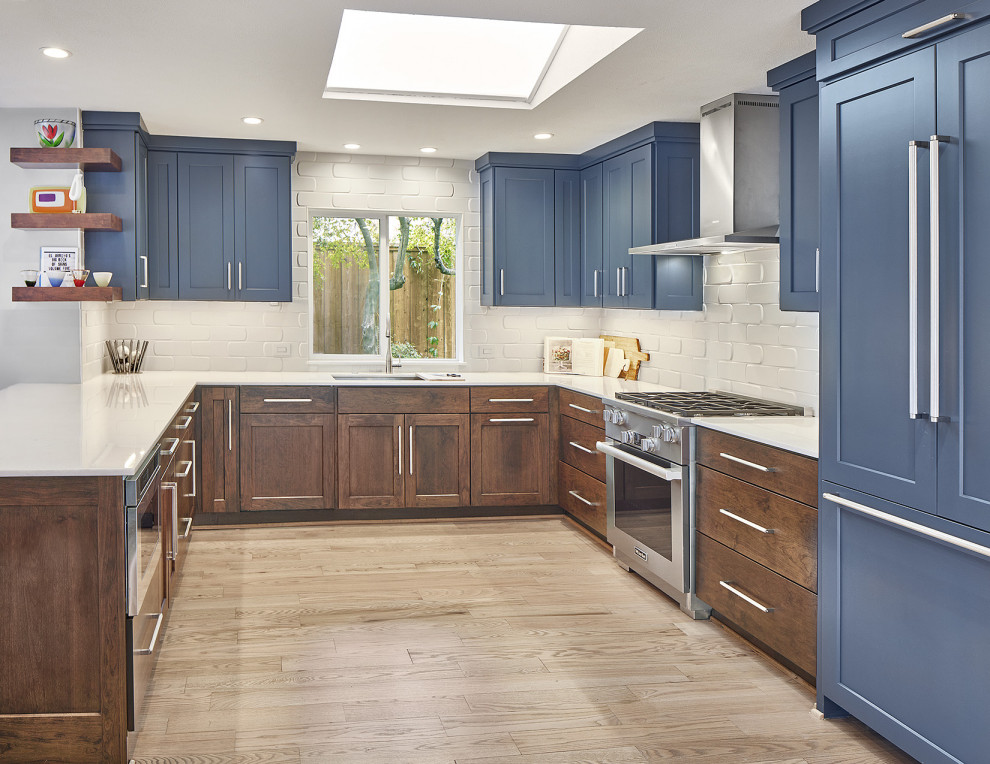 Idéer för ett mellanstort modernt vit kök, med en undermonterad diskho, luckor med infälld panel, blå skåp, marmorbänkskiva, vitt stänkskydd, stänkskydd i porslinskakel, rostfria vitvaror, ljust trägolv, en halv köksö och brunt golv
