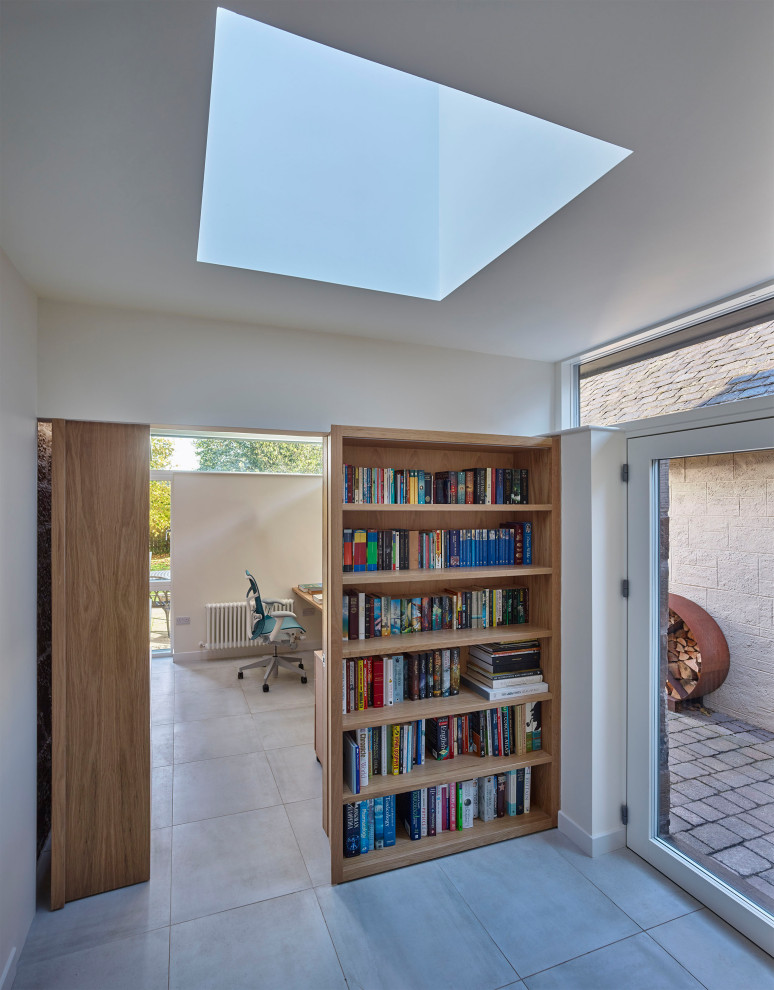 Inspiration för ett litet funkis hemmabibliotek, med vita väggar, klinkergolv i porslin, ett inbyggt skrivbord och grått golv