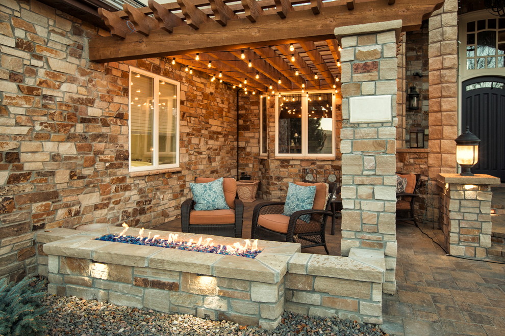 Inspiration for a mid-sized country front yard verandah in Denver with a fire feature, natural stone pavers and a pergola.