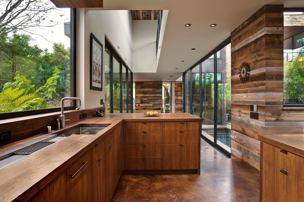 Inspiration for a contemporary eat-in kitchen in Los Angeles with an undermount sink, flat-panel cabinets, medium wood cabinets, wood benchtops, glass sheet splashback and a peninsula.