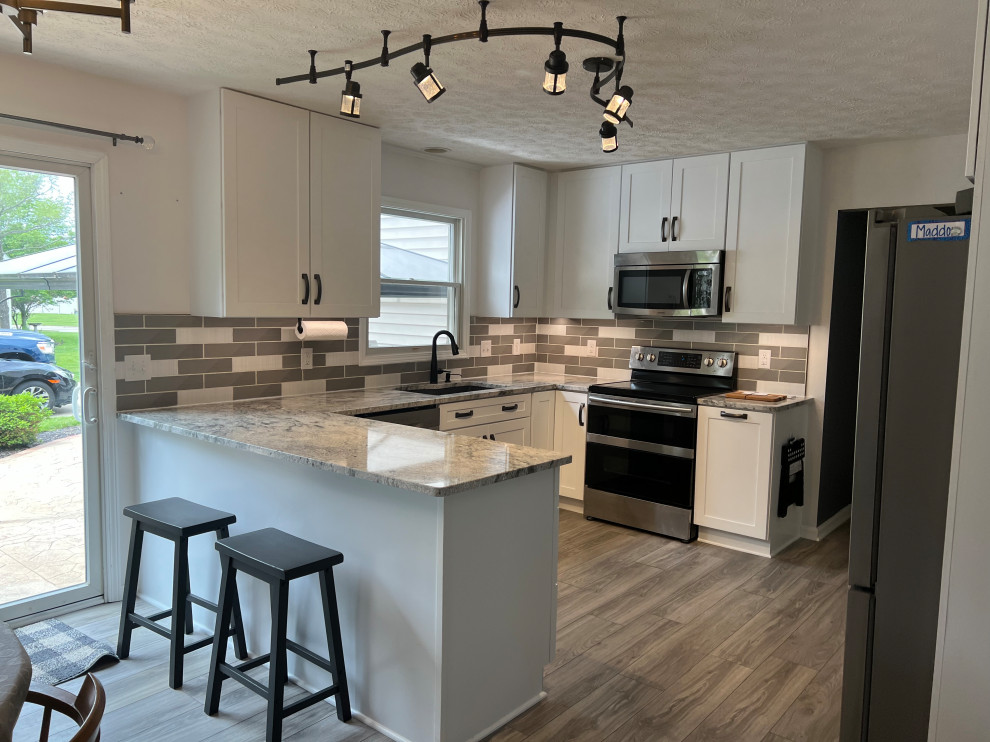 Example of a mid-sized classic u-shaped eat-in kitchen design in Cleveland with shaker cabinets, white cabinets, granite countertops and ceramic backsplash