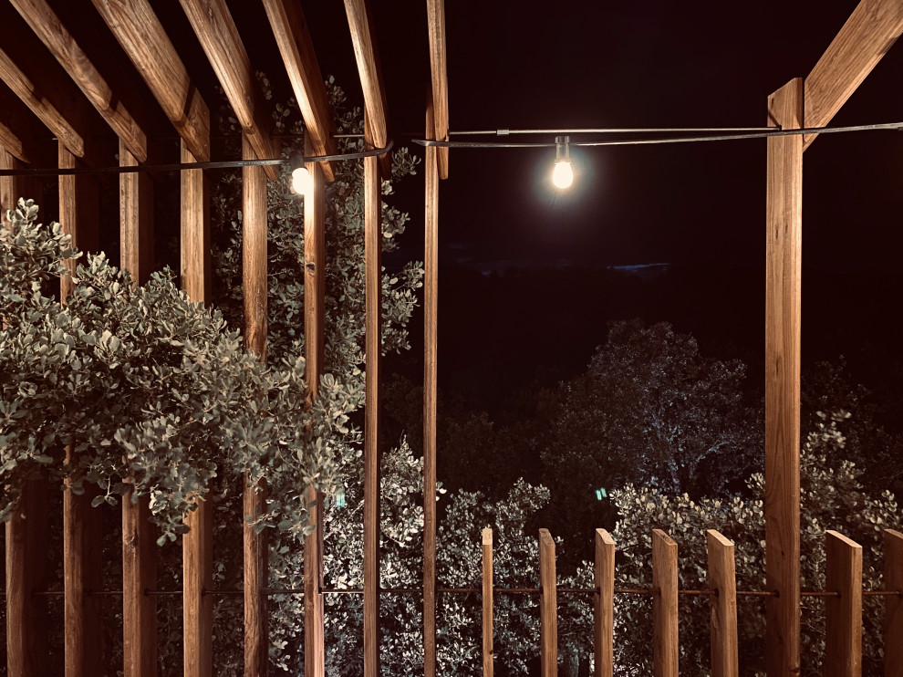 Medium sized industrial wood railing terrace in Madrid with feature lighting and a pergola.