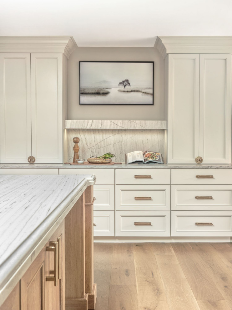 Design ideas for a large transitional l-shaped open plan kitchen in St Louis with a farmhouse sink, flat-panel cabinets, white cabinets, quartz benchtops, multi-coloured splashback, panelled appliances, light hardwood floors, with island, brown floor, white benchtop and wallpaper.