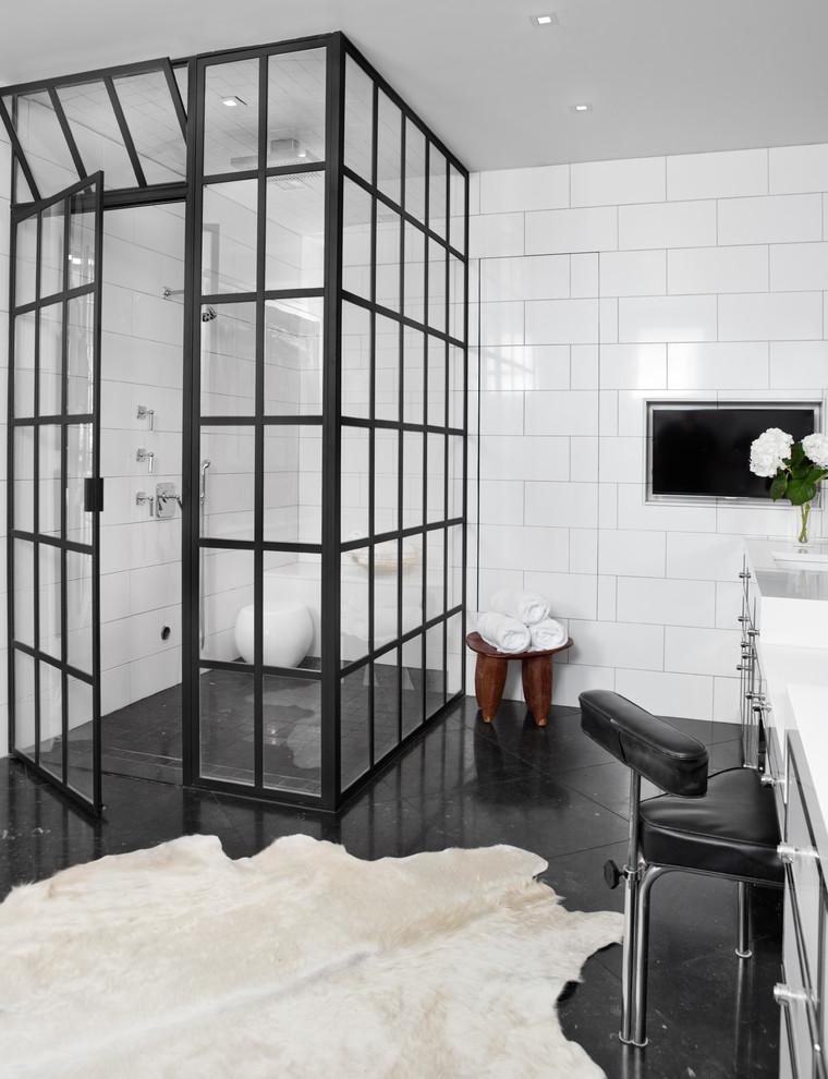 Inspiration for a mid-sized industrial master bathroom in Other with glass-front cabinets, white cabinets, a corner shower, white tile, ceramic tile, white walls, marble floors, black floor, a hinged shower door, a one-piece toilet, a drop-in sink and solid surface benchtops.