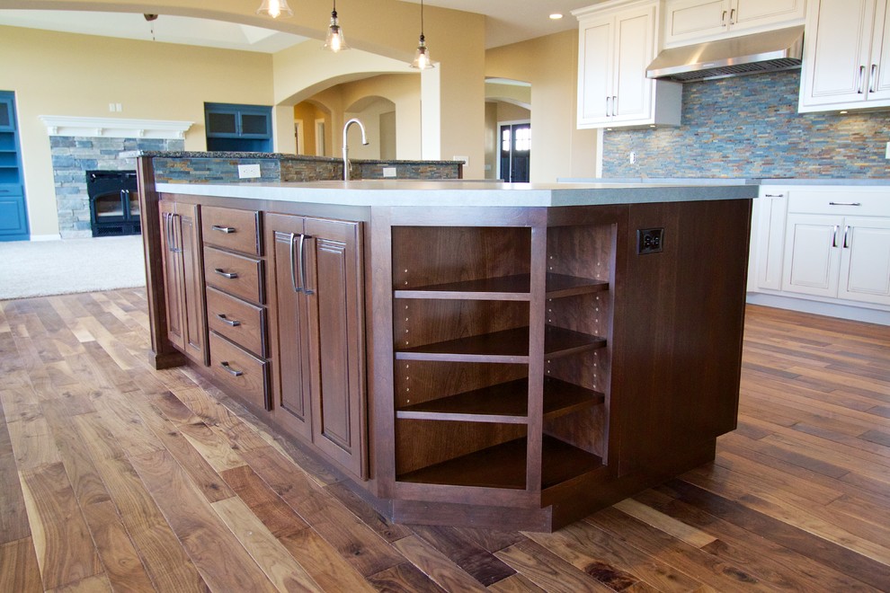 Example of a huge open concept kitchen design with raised-panel cabinets, dark wood cabinets, solid surface countertops and an island