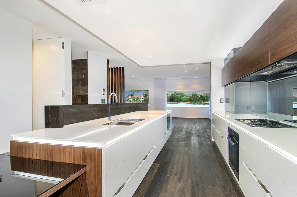 Large modern galley eat-in kitchen in Sydney with an undermount sink, medium wood cabinets, solid surface benchtops, mirror splashback, stainless steel appliances, dark hardwood floors and with island.