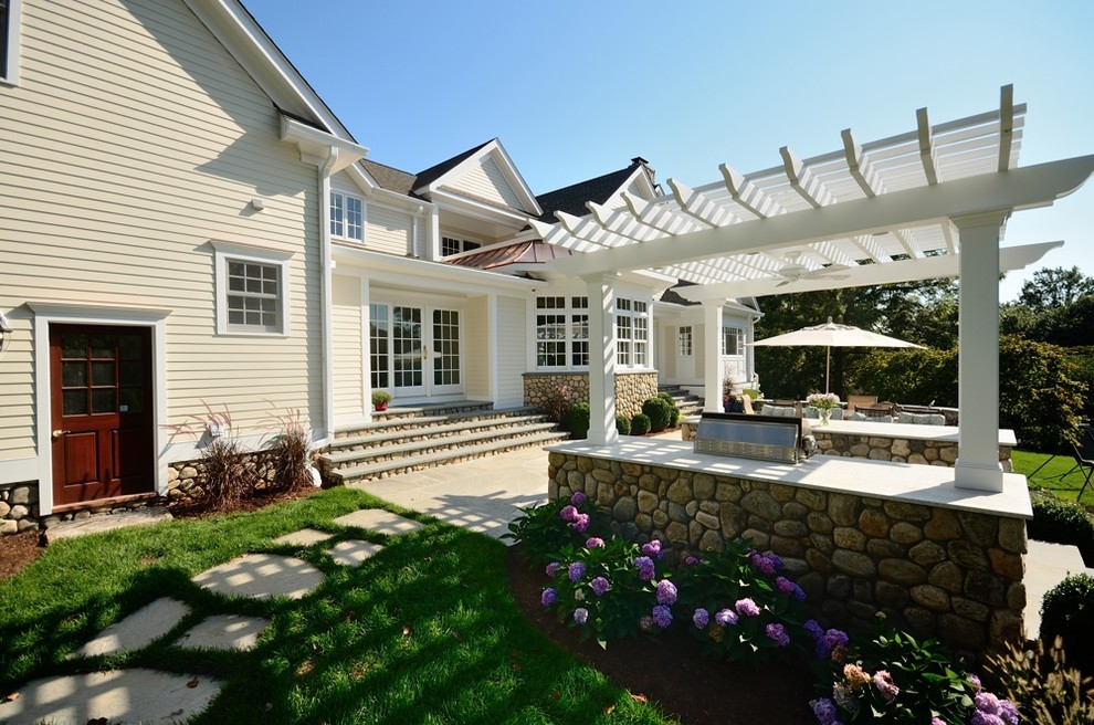 Design ideas for an expansive traditional backyard patio in New York with an outdoor kitchen, natural stone pavers and a pergola.