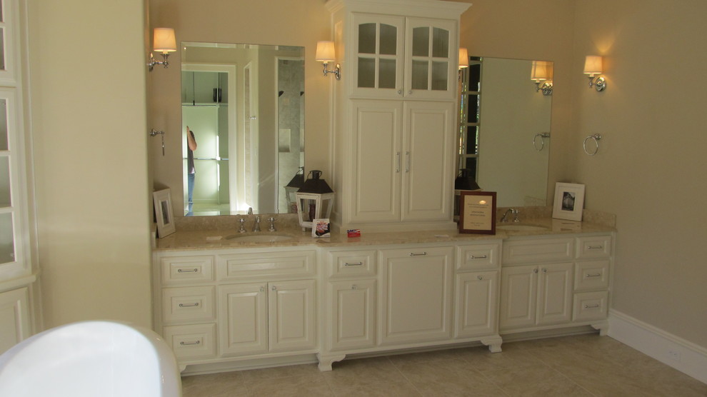 Large traditional master bathroom in New Orleans with raised-panel cabinets, white cabinets, a freestanding tub, an alcove shower, beige tile, porcelain tile, beige walls, porcelain floors, an undermount sink and granite benchtops.
