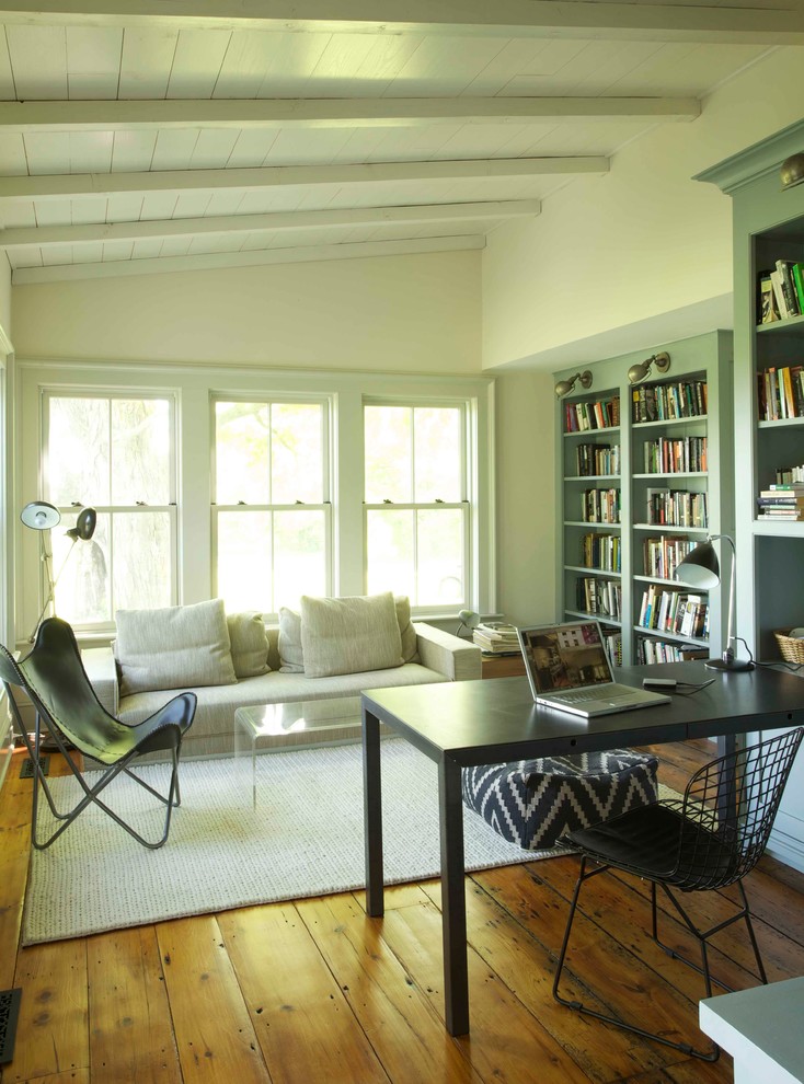 This is an example of a country home office in Boston with white walls, medium hardwood floors and a freestanding desk.